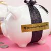 Brother TZe-PR851 black and gold label on pink piggy bank with glitter ribbon