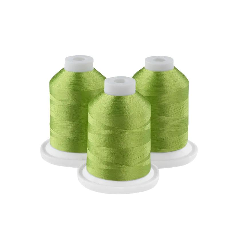 Three grass green embroidery thread spools on white bases