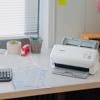 Brother ADS-4300N compact document scanner on office desk with papers and supplies