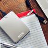 Brother label maker on notebook with red and white laminated tape on wooden desk