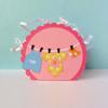 Pink scalloped gift box with baby clothes hanging on clothesline decoration
