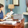 Woman reviewing printed documents from Brother wireless monochrome laser printer in home office