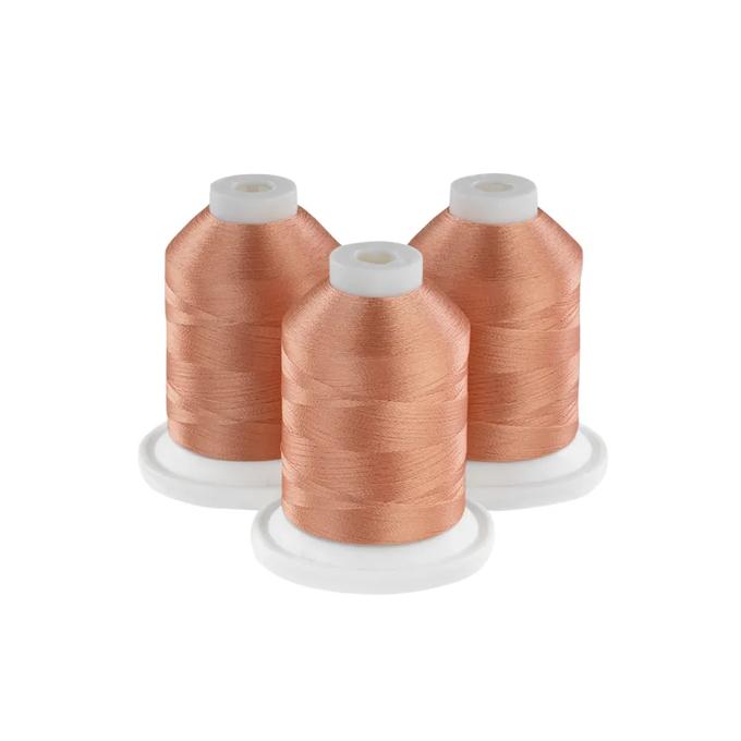 Three spools of peach embroidery thread on white bases