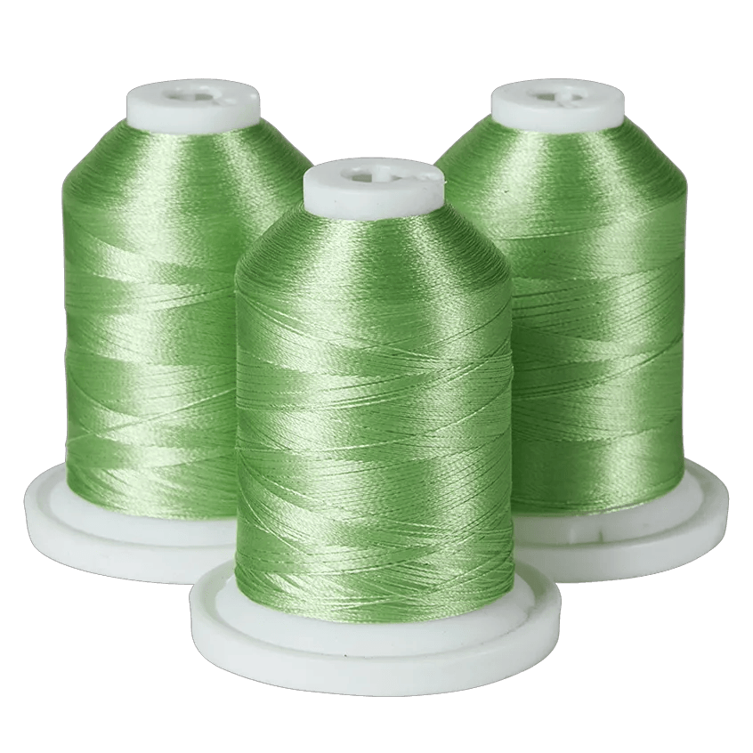 Three green Brother embroidery thread spools on white bases