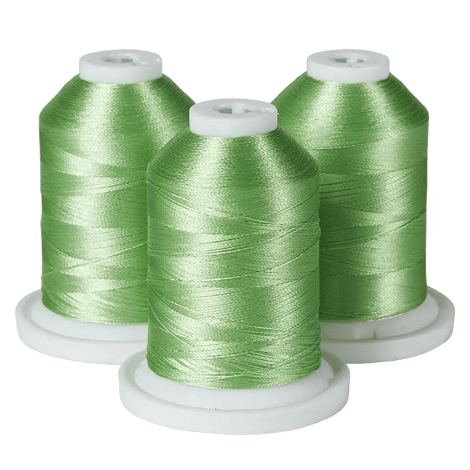 Three green Brother embroidery thread spools on white bases