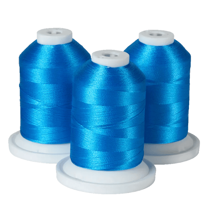 Three spools of bright blue embroidery thread on white bases