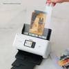 Hand inserting vintage photo into Brother document scanner with carrier sheet on marble surface
