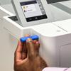 Hand inserting USB drive into Brother wireless laser printer with touchscreen display