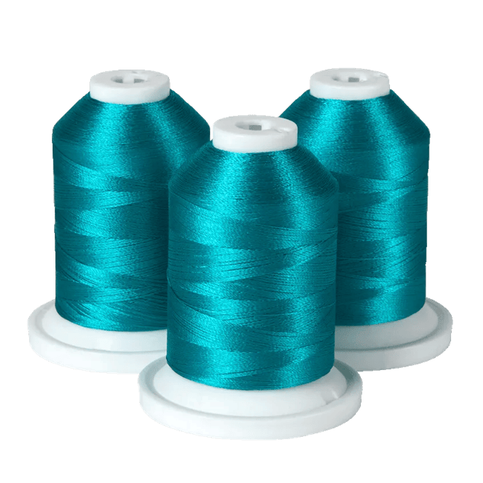 Three spools of turquoise Brother embroidery thread on white bases