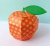 Orange polka dot paper craft apple with green leaf on light blue surface