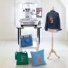 Brother embroidery machine creating custom designs on denim jacket, tote bags, and pillow