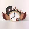 Steampunk-style clock with wings, top hat, goggles, and gears on white surface