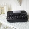 Brother P-touch label maker with QWERTY keyboard on bathroom shelf with skincare products