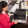 Woman loading paper into Brother HL-L8430CDW color laser printer in modern office
