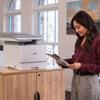 Woman reviewing color printout from Brother all-in-one laser printer in home office