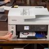 Person inserting USB drive into Brother MFC-J6540DW all-in-one inkjet printer on desk