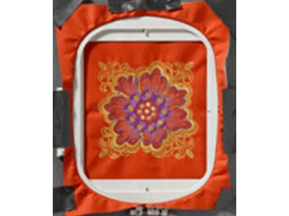 Brother embroidery machine hoop displaying colorful floral mandala design on orange fabric
