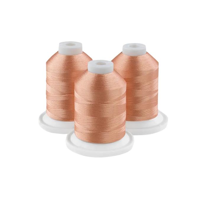 Three spools of peach-colored embroidery thread on white bases