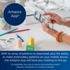Hand holding smartphone displaying Artspira App with Brother sewing machine on desk