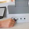 Hand inserting USB drive into Brother ADS-4700W wireless document scanner connectivity ports