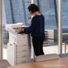 Woman using Brother MFC-L6915DW all-in-one laser printer with paper trays in modern office