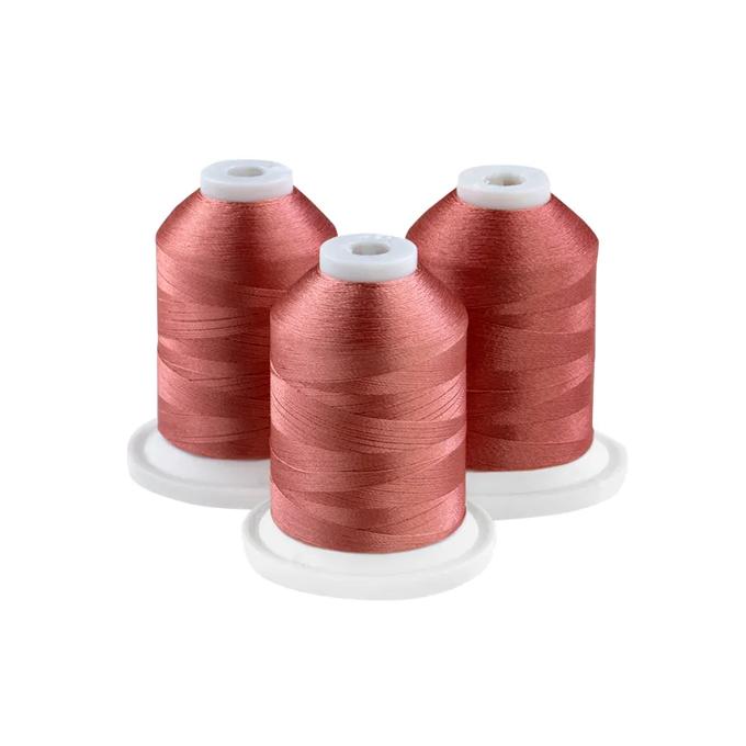 Three spools of pink embroidery thread on white bases