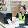 Woman using Brother industrial label printer in warehouse to print barcode shipping labels