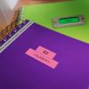 Brother P-touch label on purple notebook with green notebook and label maker in background