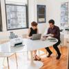 Brother wireless document scanner on desk with two professionals reviewing documents in office