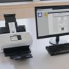 Brother ADS3350W wireless desktop scanner scanning receipt on office desk with computer monitor