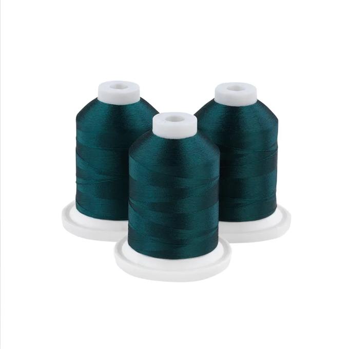 Three dark lagoon embroidery thread spools on white bases