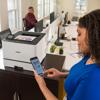 Woman using smartphone to print with Brother HL-L8430CDW color laser printer in office