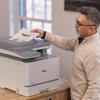 Man retrieving color document from Brother MFC-L8970CDW all-in-one laser printer in office