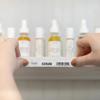 Hands applying Brother label to serum shelf with dropper bottles visible behind