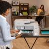 Woman using smartphone with Brother all-in-one color inkjet printer in home office