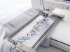 Brother embroidery machine stitching floral design on white fabric in hoop
