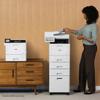 Woman scanning documents on Brother all-in-one printer with storage tower in office setting