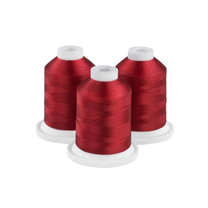 Three spools of deep garnet embroidery thread on white bases