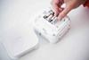 Hands loading batteries into Brother P-touch Cube portable label maker