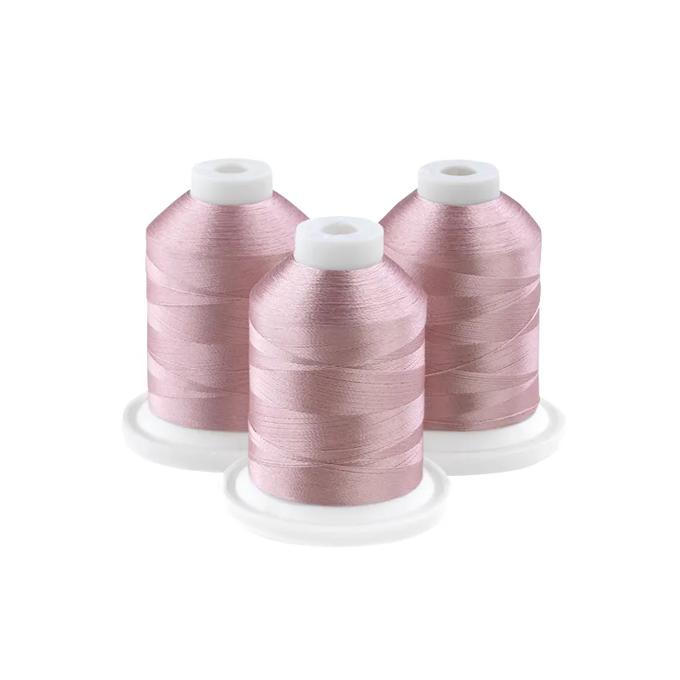 Three spools of pink embroidery thread on white bases