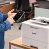 Person using smartphone to connect to Brother HL-L5215DW wireless monochrome laser printer in office