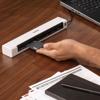 Hand inserting card into Brother portable scanner connected to laptop on wooden desk