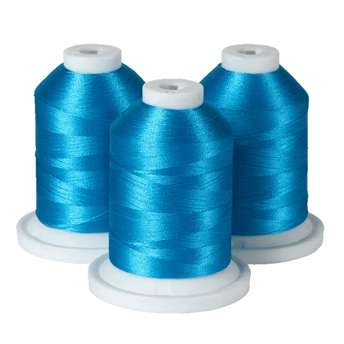 Three spools of bright blue Brother embroidery thread on white bases