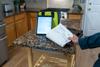 Field technician holding fan-fold invoice printed by Brother PocketJet portable printer in kitchen