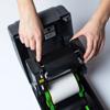 Hands loading label roll into Brother desktop label printer with open cover