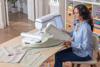 Woman using Brother Celeste CX1e embroidery machine with touchscreen in home craft room