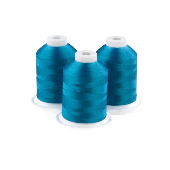 Three aqua embroidery thread spools on white bases