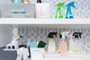 Organized cleaning supplies on shelves with spray bottles, sponges, and storage bins