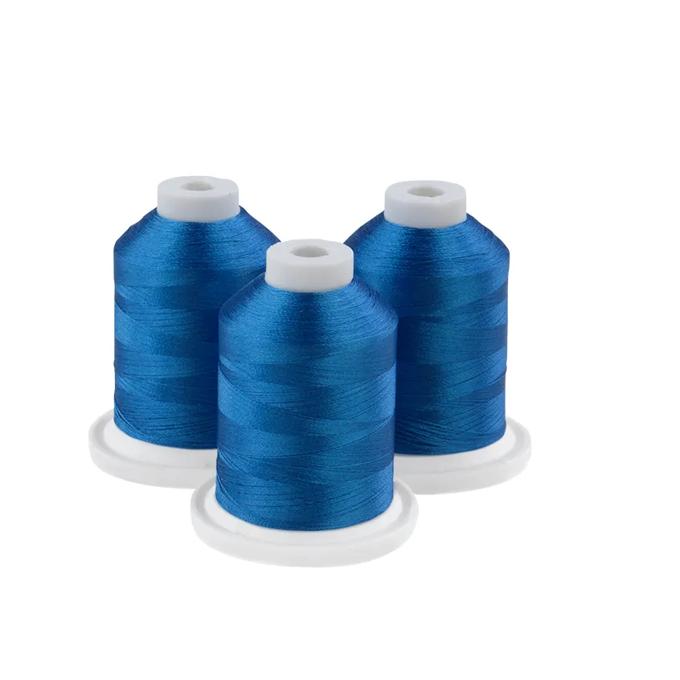 Three spools of Brother Persian blue embroidery thread on white bases