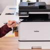 Hand scanning ID card on Brother MFC-L8730CDW all-in-one color laser printer in office